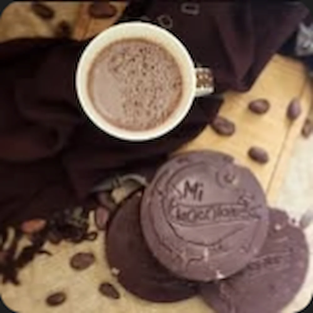 Mi Chocolate chocolate tablets beside a cup of hot chocolate and cacao beans